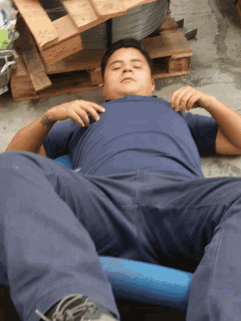 a man in a blue shirt is laying on the ground