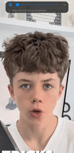 a close up of a boy 's face with a blue circle that says wszystko tryb nie przeskadzac on it