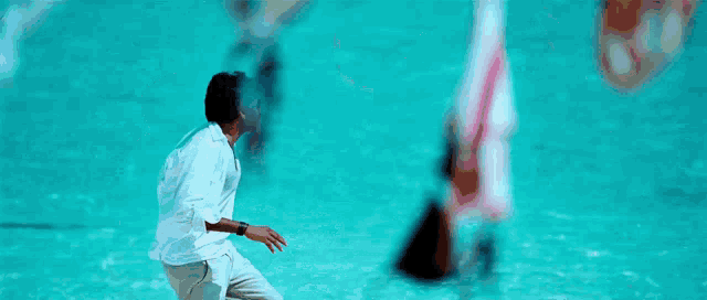 a man in a white shirt and white pants is running on a beach