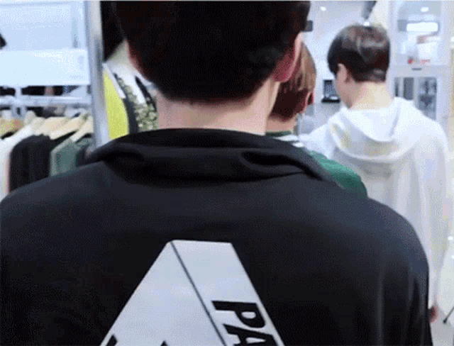 a man wearing a black shirt with a white triangle on the back is walking through a store .
