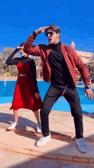 a man and a woman are dancing in front of a swimming pool
