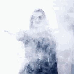a woman is standing in a cloud of smoke and holding a gun .