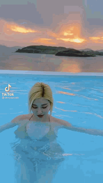 a swimming pool with a view of the ocean at sunset