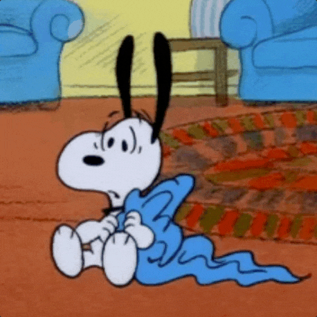 snoopy is sitting on the floor with a blue blanket around his neck .