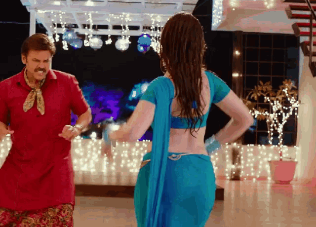 a man in a red shirt stands next to a woman in a blue dress