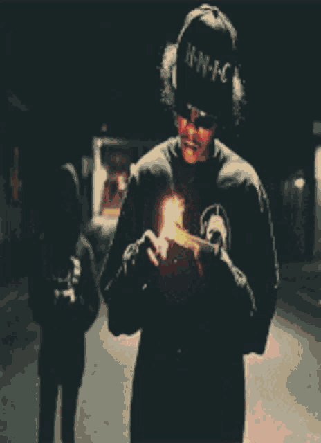 a man wearing a hat that says h-n-m-c is holding a lighter