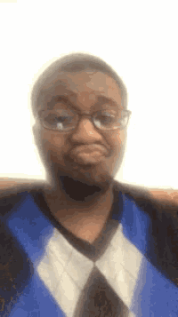 a man wearing glasses and a blue and white plaid sweater makes a funny face