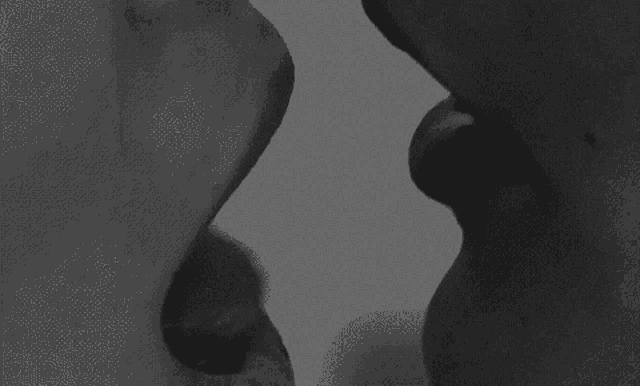 a black and white photo of a man and woman kissing .
