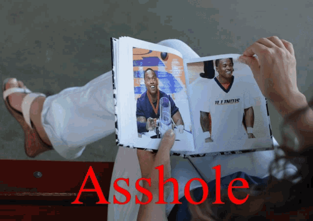 a person holding a book with the word asshole written in red