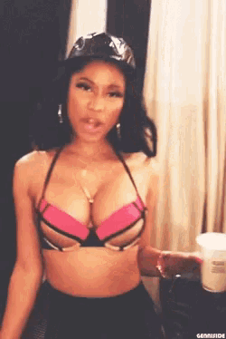 a woman wearing a bikini top and a hat is holding a cup .