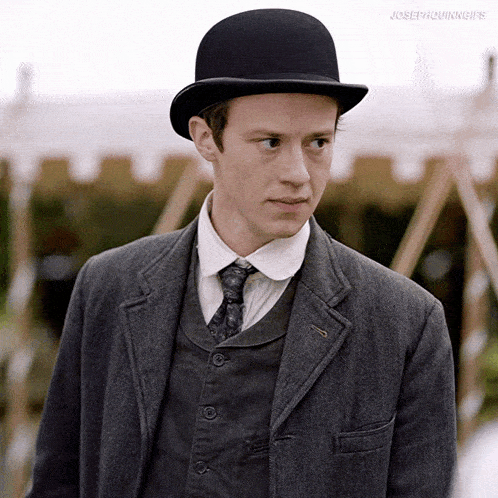 a man in a suit and tie is wearing a black bowler hat .