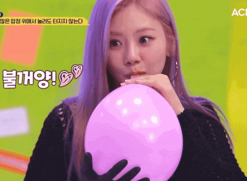 a woman blowing up a pink balloon with chinese writing on it