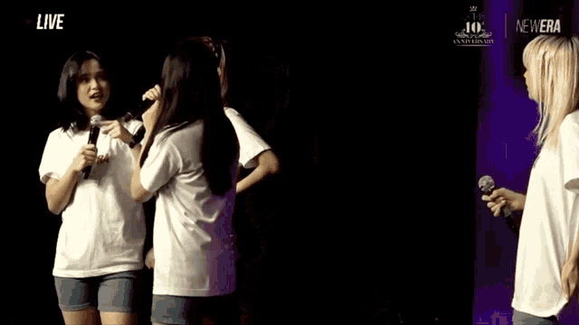 two girls singing in front of a sign that says newera
