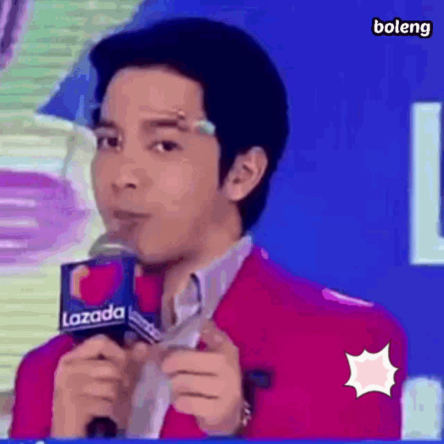 a man in a pink jacket is holding a microphone and talking into it .