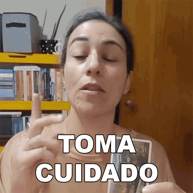 a woman holds a tarot card and says " toma cuidado "