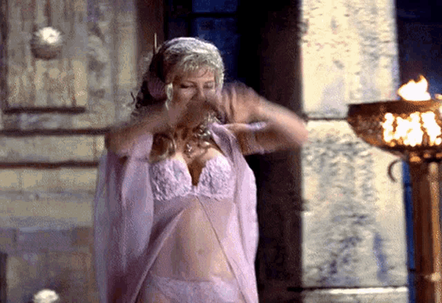 a woman in lingerie is standing in front of a fire