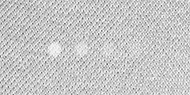 a close up of a white knitted fabric with a small hole in it .