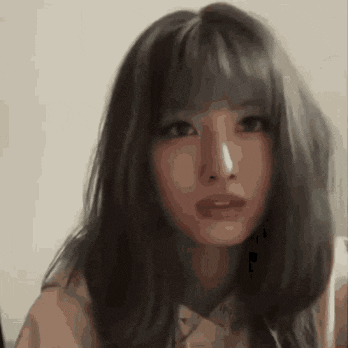 a close up of a woman 's face with long hair and bangs looking at the camera .