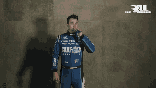 a man wearing a blue racing suit that says code 3 on it