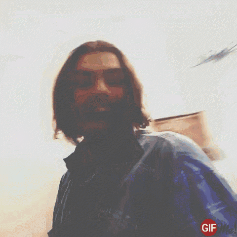 a man with long hair and a beard is taking a selfie with a gif me logo in the corner