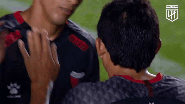 two soccer players are hugging each other on a field with a lpf logo in the corner