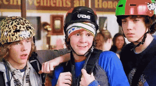 a boy wearing a helmet that says ucg is standing next to two other boys