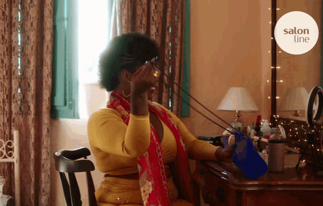 a woman is sitting at a dressing table with a salon line logo in the background