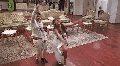 a man and a woman are dancing in a living room with furniture .