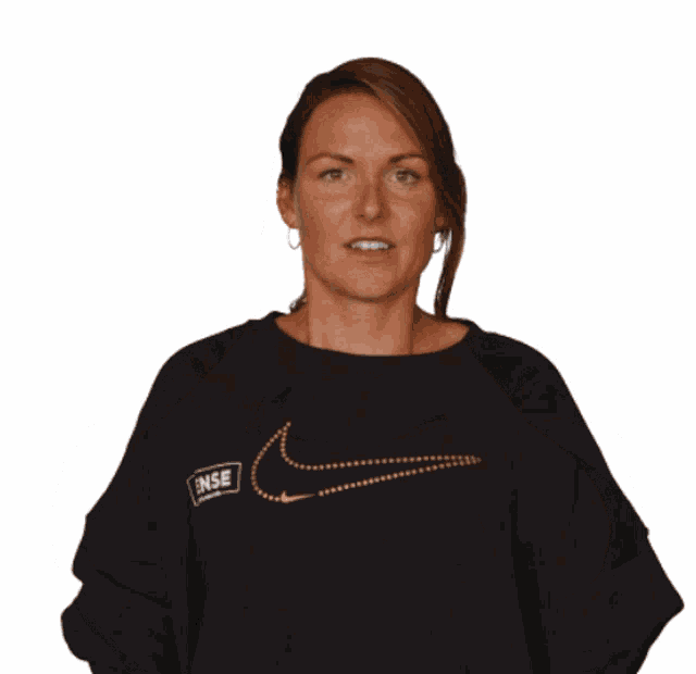 a woman wearing a black nike shirt holds her hands up in the air