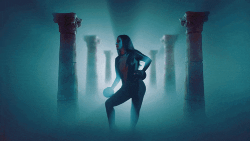 a woman stands in a dark room surrounded by pillars