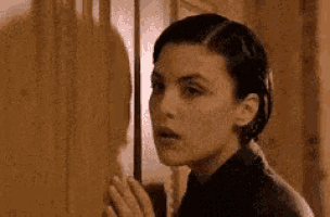 a woman is standing in front of a door and looking out .