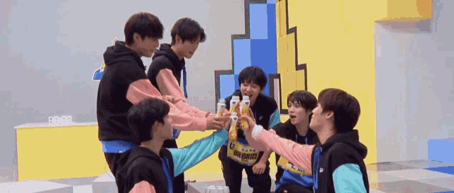a group of young men are toasting with bottles of orange juice in a room