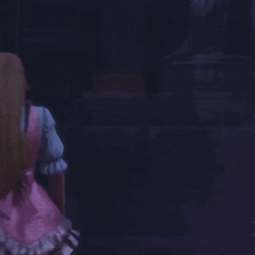 a woman in a pink dress is dancing in the dark