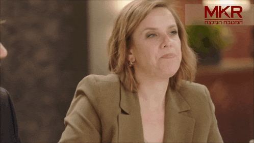 a woman sitting at a table in front of a sign that says mkr