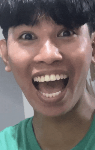 a close up of a young man making a funny face with his mouth open