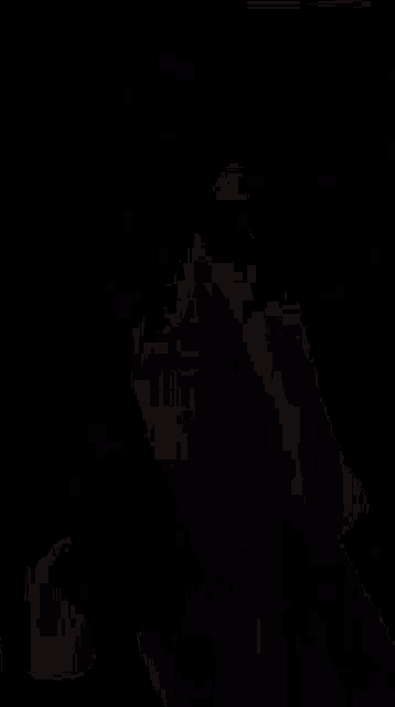 a person in a black mask is walking in a dark room .