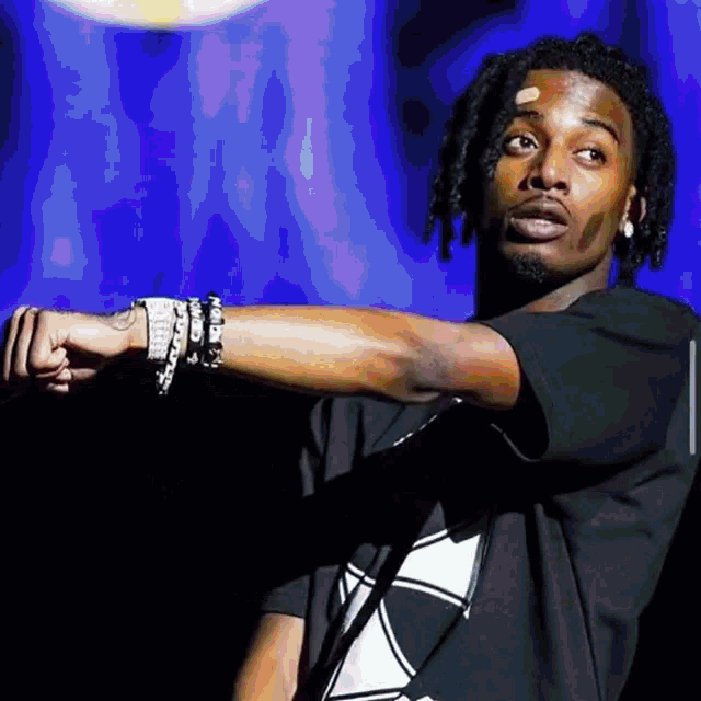 a young man with dreadlocks is wearing a black shirt