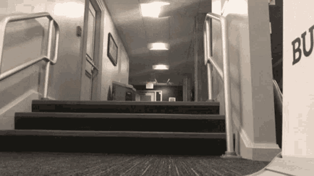 a black and white photo of a hallway with stairs and a sign that says bo
