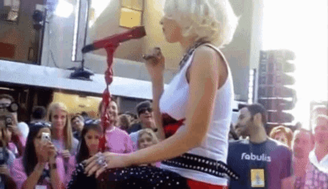 a woman is singing into a microphone in front of a crowd while wearing a shirt that says fabulis .