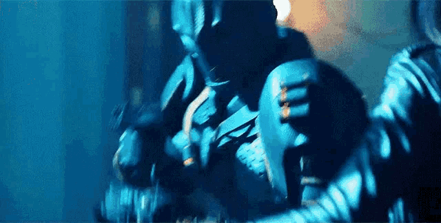 a group of people are standing next to each other in a dark room in a blue light .