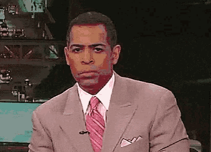 a man in a suit and tie is making a face .