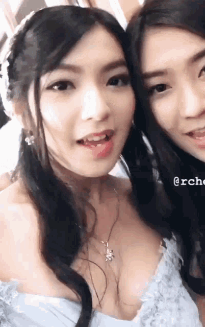 two women are posing for a picture and one of them has a necklace with a bee on it