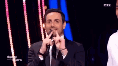 a man in a suit and tie is making a funny face with his hands .