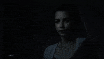 a woman in a dark room holds a pumpkin in her hand