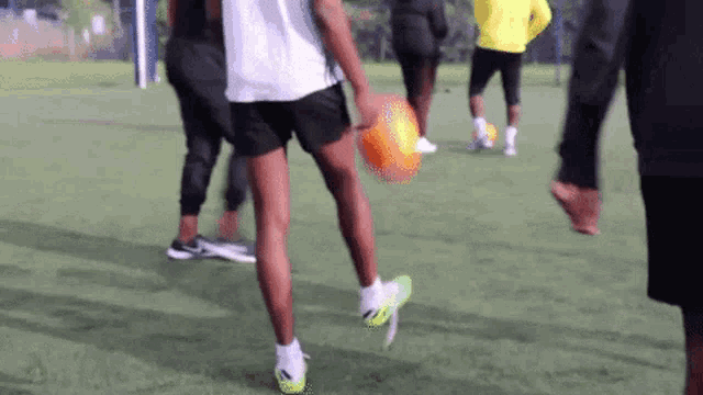 a group of people are playing soccer on a field and one of them is holding an orange ball .
