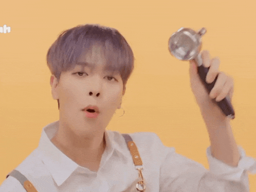 a young man with purple hair is holding a coffee maker and making a funny face .