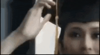 a woman is taking a picture of herself with a camera while wearing a graduation cap .