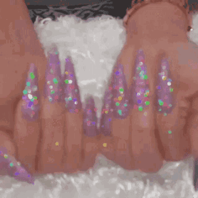 a close up of a woman 's nails with purple polish and glitter