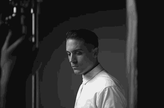 a man in a white shirt and tie looks down
