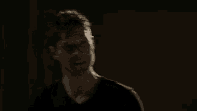 a man in a black shirt says thank you in a dark room